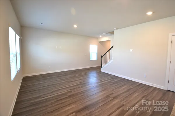 a view of an empty room with wooden floor and windows