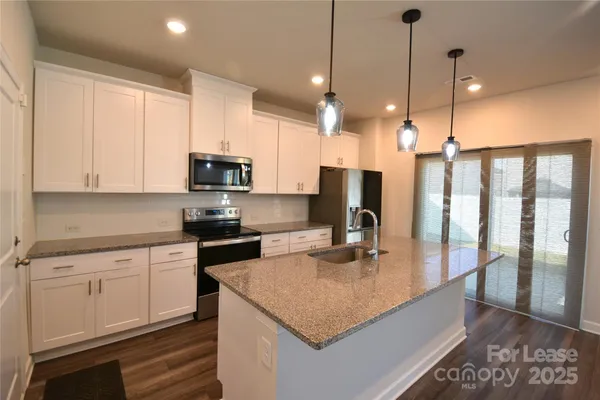 a kitchen with kitchen island granite countertop a stove top oven a sink a center island and cabinets