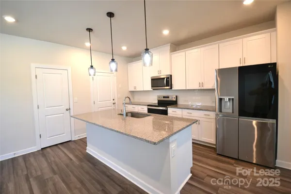 a kitchen with stainless steel appliances a stove a sink a refrigerator a center island a stove and a refrigerator