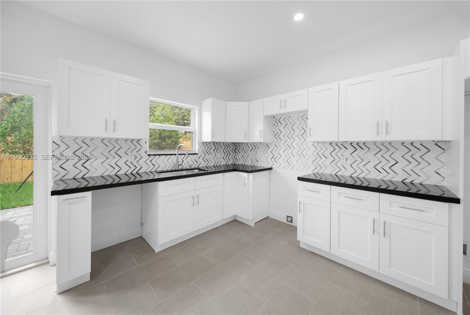 529 Northwest 56th Street Miami, FL 33127 - Photo 37 of 66 a kitchen with granite countertop a sink and white cabinets