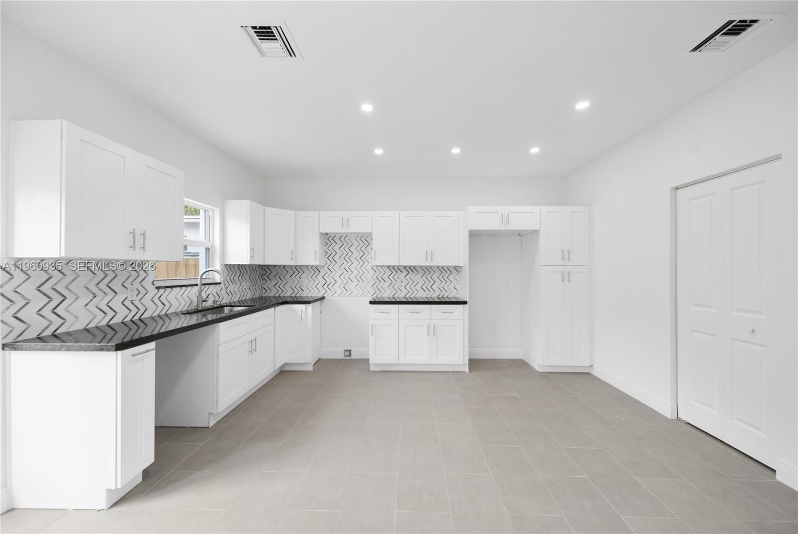 529 Northwest 56th Street Miami, FL 33127 - Photo 39 of 66 a large kitchen with granite countertop a white stove top oven and white cabinets