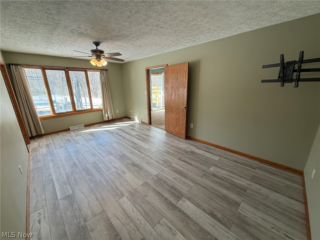 6784 Old Zoarville Road Northeast Dover, OH 44622 - Photo 24 of 50 Unfurnished room with light wood finished floors, a textured ceiling, and ceiling fan