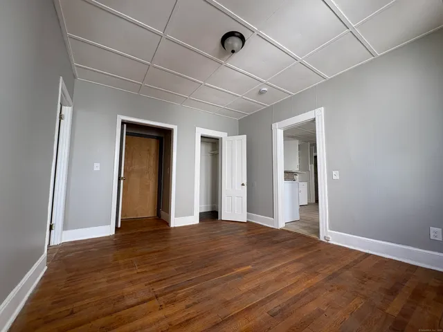 a view of an empty room with wooden floor and closet