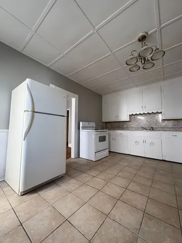 a kitchen with a stove a refrigerator and white cabinets