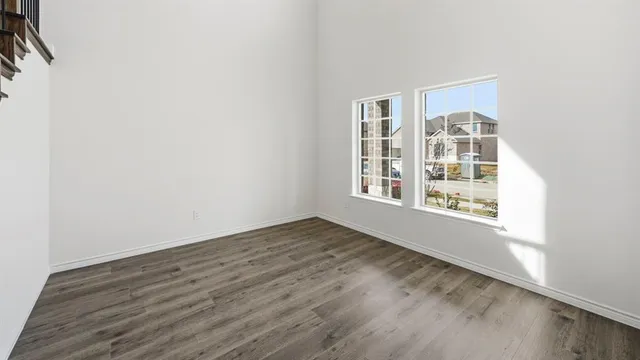 an empty room with chandelier fan and windows