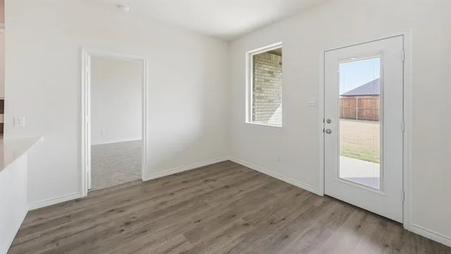 an empty room with wooden floor and fan