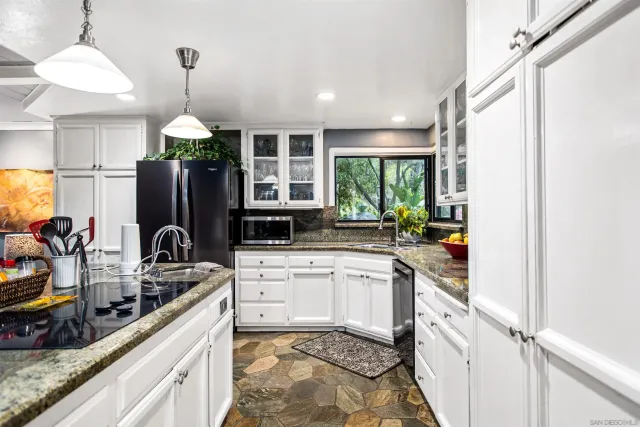 a kitchen with stainless steel appliances kitchen island granite countertop a refrigerator a stove a sink a dining table and chairs with wooden floor
