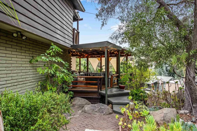 a view of a patio with table and chairs potted plants and large tree