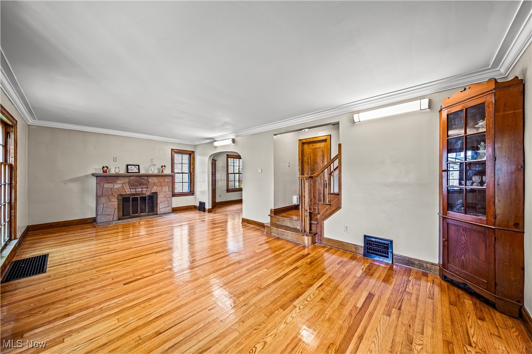 8219 Midland Road Mentor, OH 44060 - Photo 5 of 34 Living room featuring ornamental molding, a stone fireplace, and light wood-type flooring
