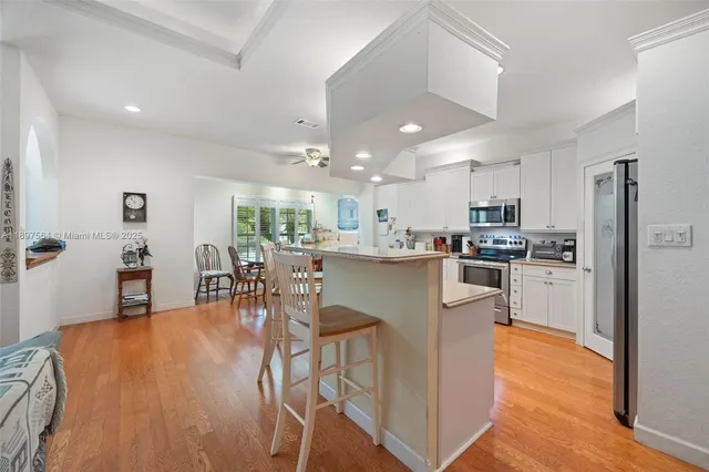 a kitchen with stainless steel appliances granite countertop a refrigerator a stove top oven and a dining table with wooden floor