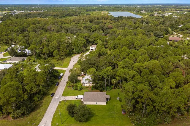 an aerial view of residential houses with outdoor space and trees