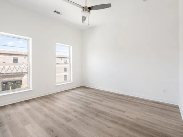 an empty room with wooden floor cabinet and windows
