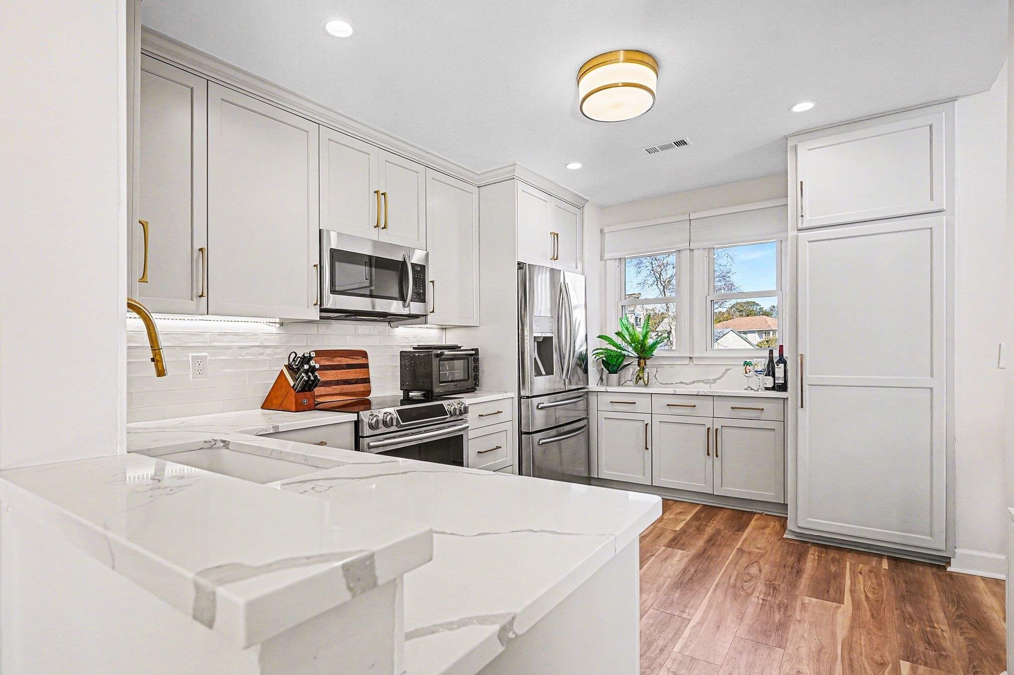 4999 Highway 17 Business, Unit 304D Murrells Inlet, SC 29576 - Photo 8 of 33 Kitchen with appliances with stainless steel finishes, light stone counters, light wood-style flooring, backsplash, and a peninsula