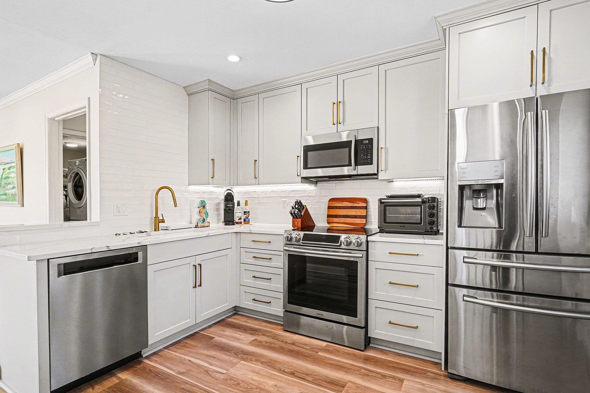 4999 Highway 17 Business, Unit 304D Murrells Inlet, SC 29576 - Photo 9 of 33 Kitchen with appliances with stainless steel finishes, light wood-style flooring, crown molding, washer / dryer, and gray cabinetry