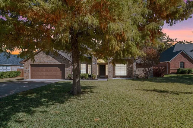a front view of a house with a garden and trees