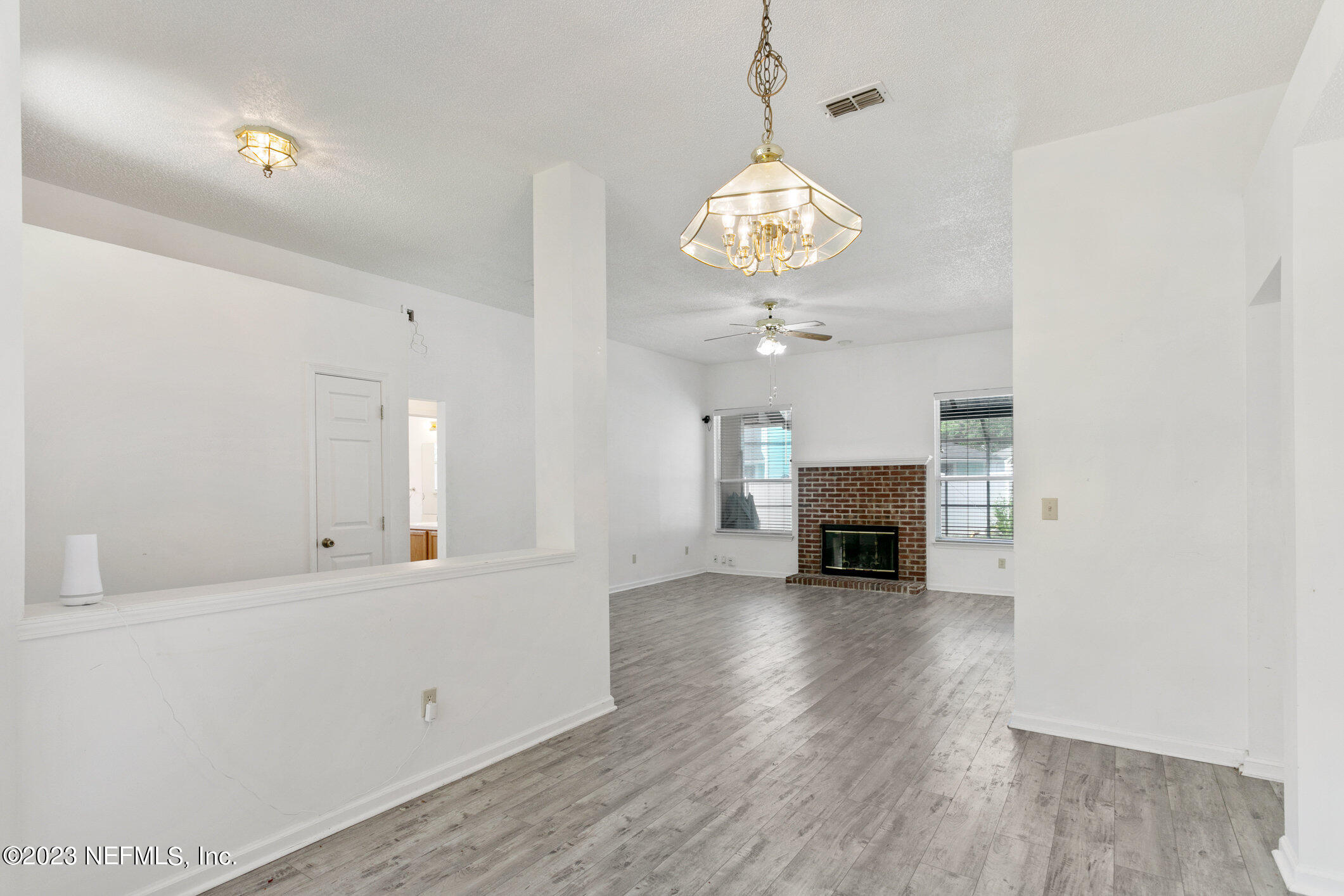 6650 Ricker Road Jacksonville, FL 32244 - Photo 8 of 41 a view of a livingroom with a fireplace a chandelier and wooden floor