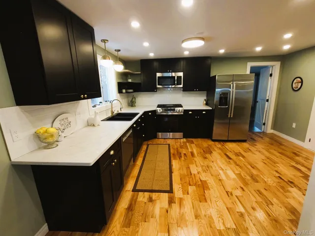 a large kitchen with stainless steel appliances kitchen island granite countertop a sink and cabinets