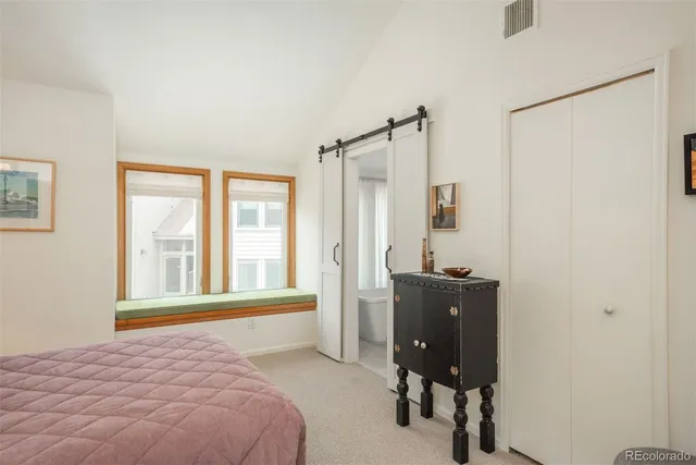 a bedroom with a bed windows and a chair