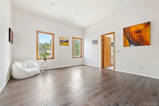 a view of an empty room with window and wooden floor