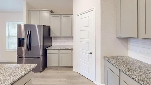 a kitchen with granite countertop a refrigerator and cabinets