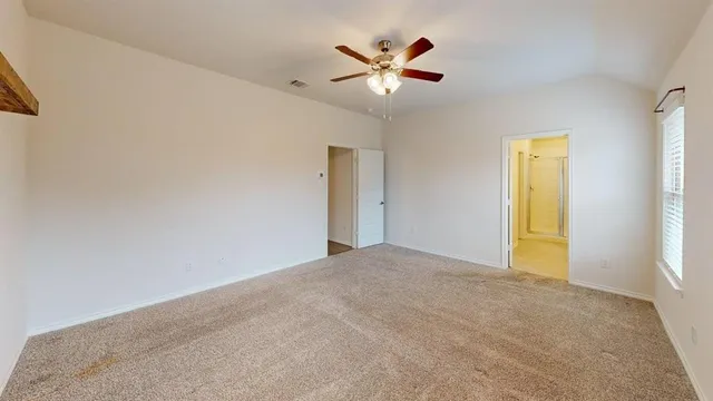 an empty room with windows and fan