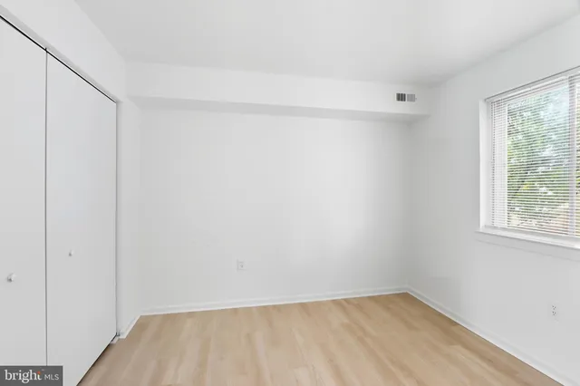 a view of an empty room with a window and closet area