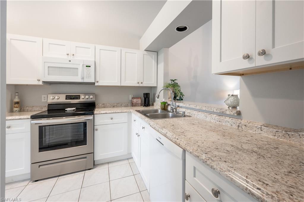 367 Dover Place, Unit 1002 Naples, FL 34104 - Photo 7 of 31 a kitchen with granite countertop white cabinets and white appliances