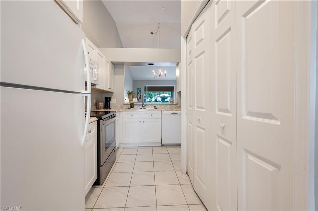 367 Dover Place, Unit 1002 Naples, FL 34104 - Photo 9 of 31 a kitchen with white cabinets and white appliances