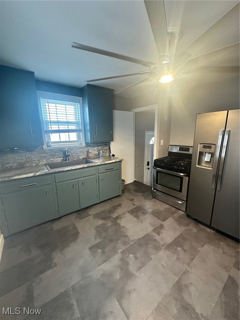 12926 Littleton Road Garfield Heights, OH 44125 - Photo 5 of 12 Kitchen featuring stove, sink, decorative backsplash, and refrigerator