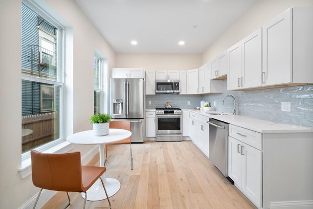 a kitchen with stainless steel appliances granite countertop a stove top oven a sink dishwasher a dining table and chairs with wooden floor