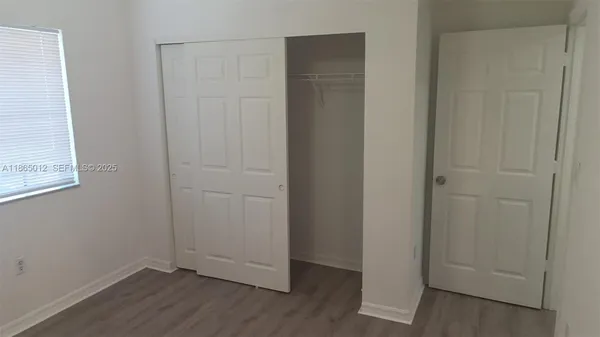 an empty room with wooden floor and closet area