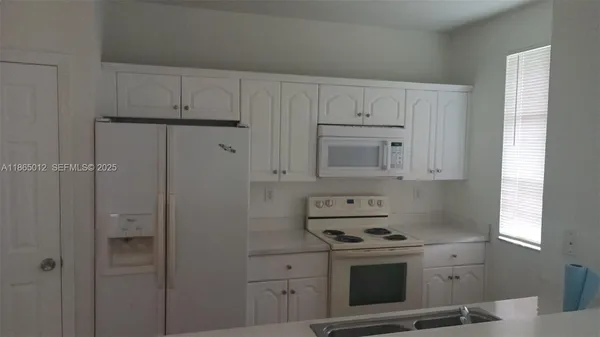 a kitchen with cabinets appliances and wooden floor