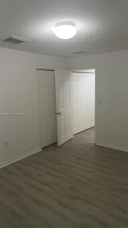 an empty room with wooden floor & windows in a room