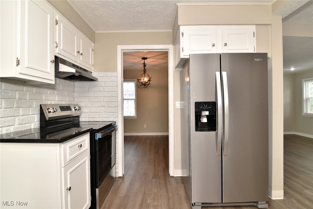 1443 Churchill Road Lyndhurst, OH 44124 - Photo 19 of 39 Kitchen with stainless steel appliances, white cabinetry, light wood-style floors, healthy amount of natural light, and a textured ceiling