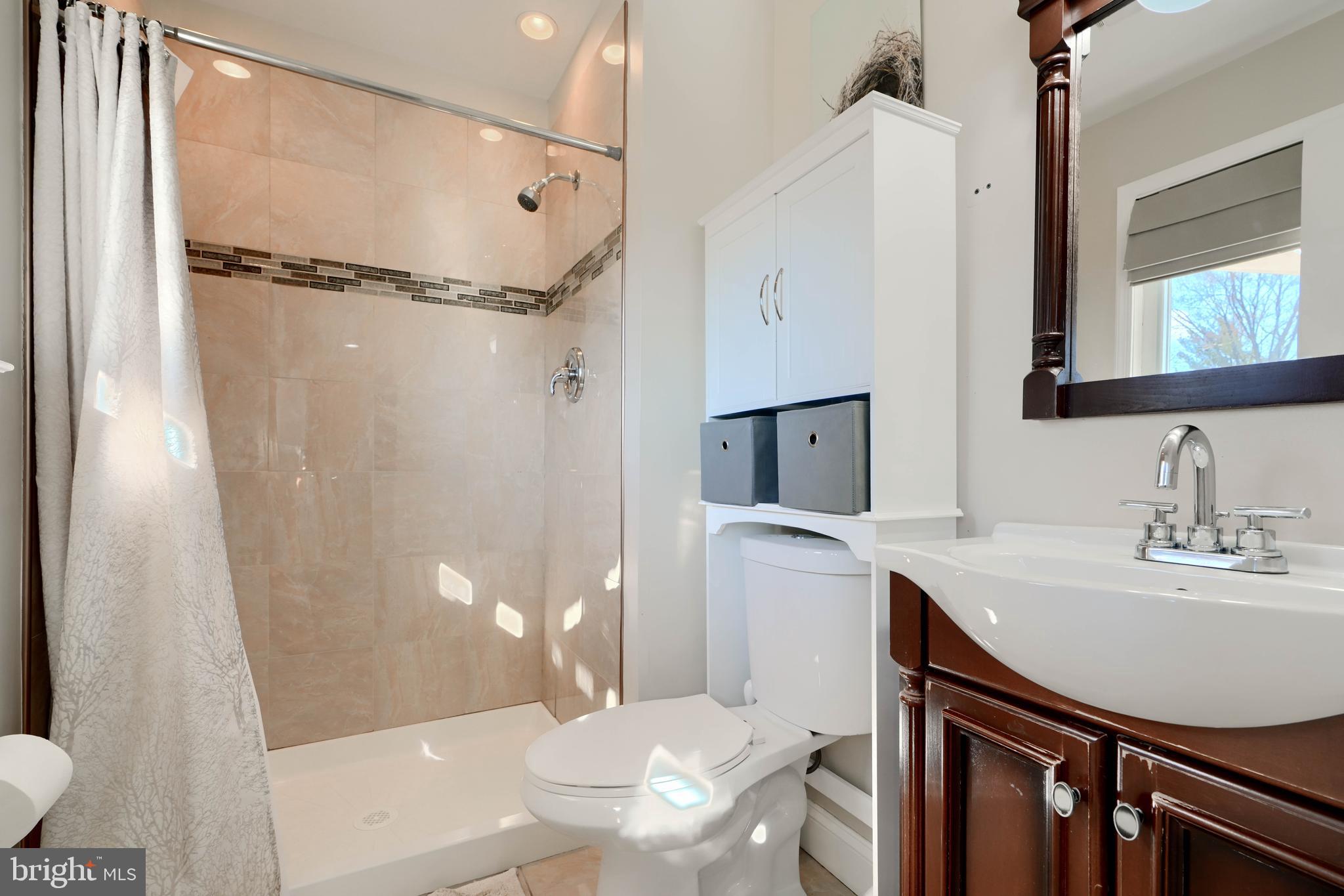8232 Scotts Level Road Baltimore, MD 21208 - Photo 27 of 69 a bathroom with a sink a toilet a mirror and shower