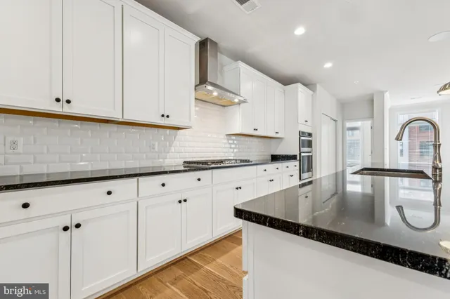 a kitchen with granite countertop a sink a stove and cabinets