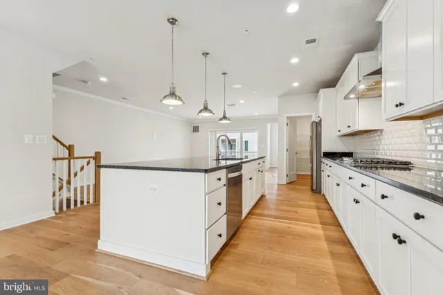 a large kitchen with stainless steel appliances kitchen island a large counter top a stove a refrigerator and white cabinets