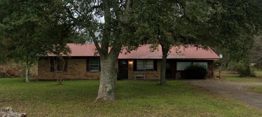 Single story home featuring driveway, an attached carport, a front yard, and metal roof