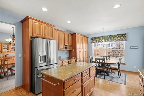 a kitchen with stainless steel appliances granite countertop a table chairs and a refrigerator