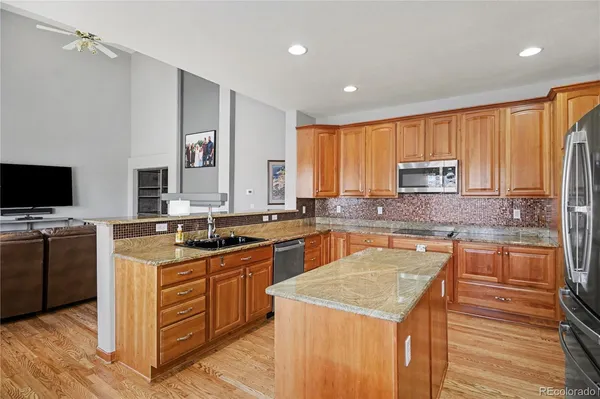 a kitchen with stainless steel appliances granite countertop wooden cabinets a stove top oven a sink and dishwasher with wooden floor
