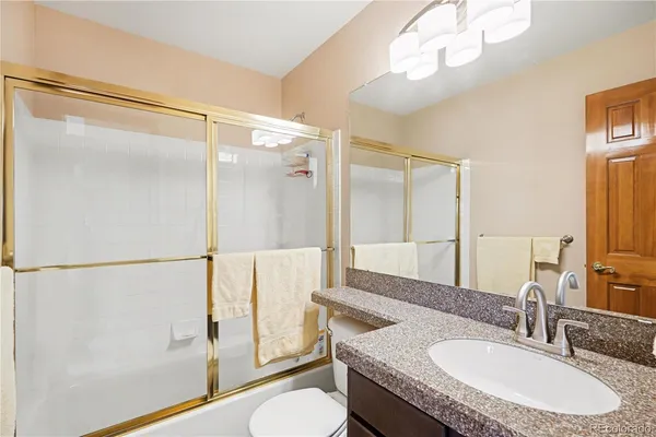 a bathroom with a granite countertop shower sink vanity mirror and toilet