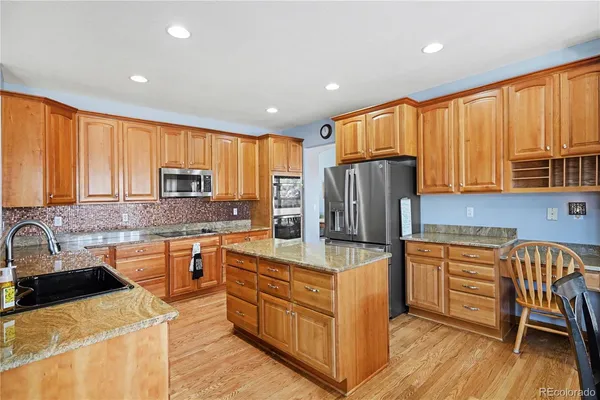 a kitchen with stainless steel appliances granite countertop a refrigerator a stove top oven a sink dishwasher and wooden cabinets with wooden floor