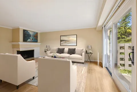 a living room with furniture a large window and a fireplace