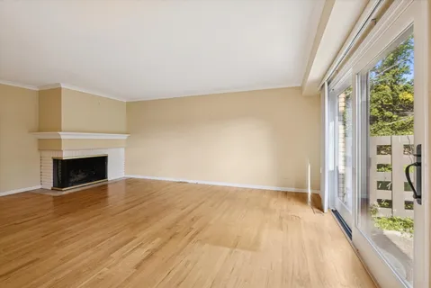 a view of an empty room with glass door and wooden floor