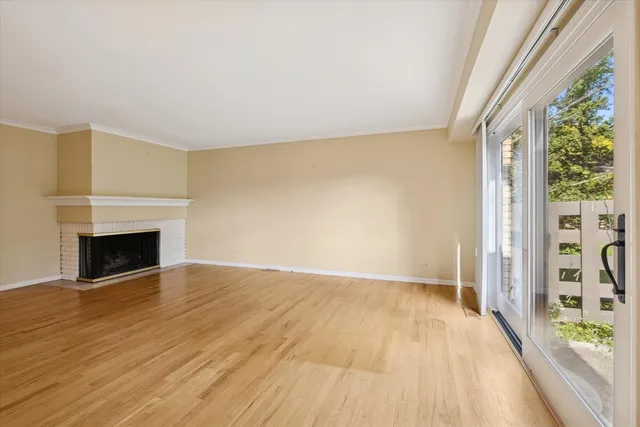 a view of an empty room with glass door and wooden floor