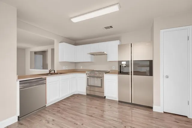 a kitchen with a refrigerator and white cabinets