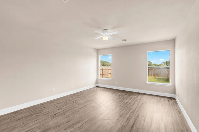 an empty room with wooden floor and windows