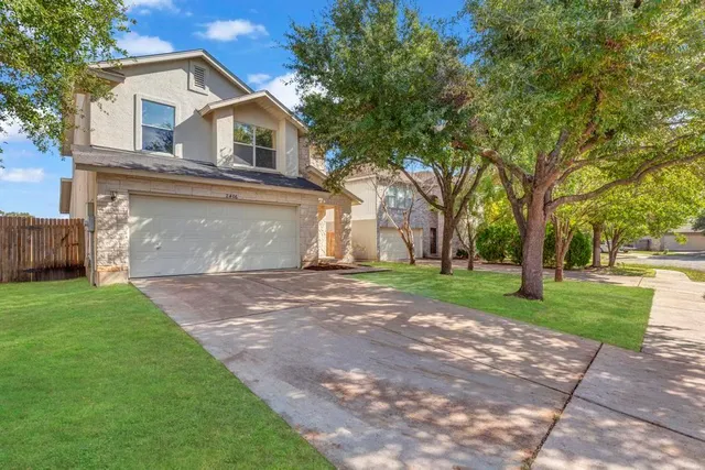 a view of a yard in front of a house with large tree
