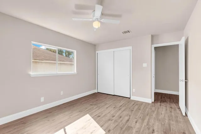 a view of empty room with wooden floor and fan