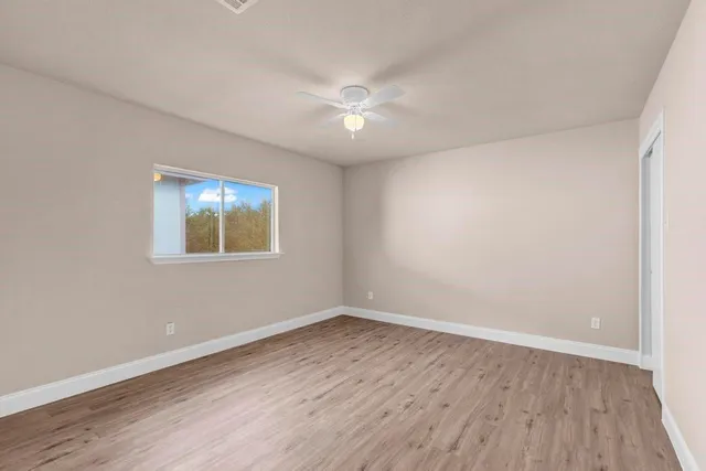 a view of an empty room with wooden floor and a window